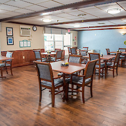 Dining room with square tables and photos on walls at SecureCare 60 West facility in Rocky Hill, CT