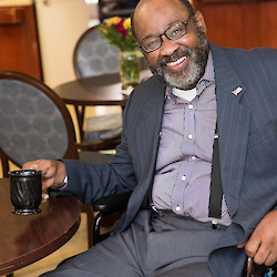 Resident in wheelchair drinking coffee in the dining room of 60 West, Rocky Hill